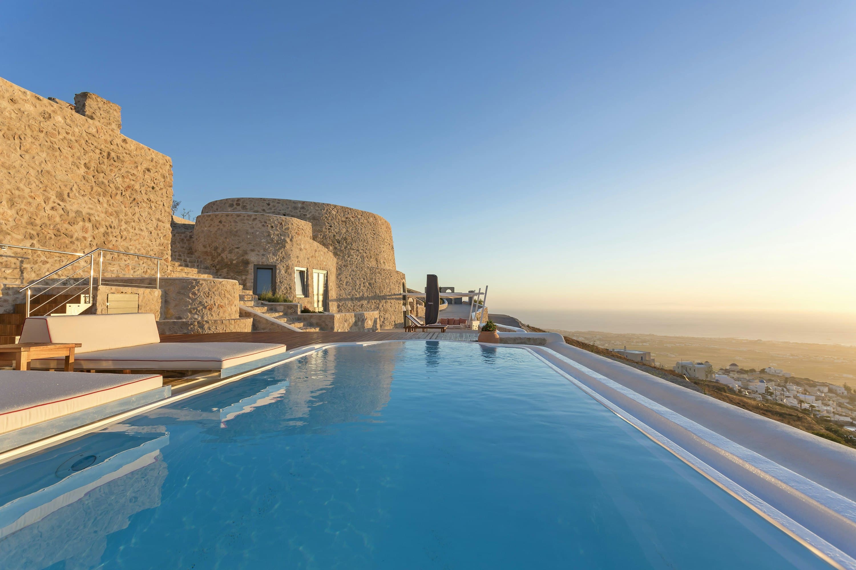 Calypso Dream infinity pool with Cycladic stone terrace at sunset, Santorini, Greece