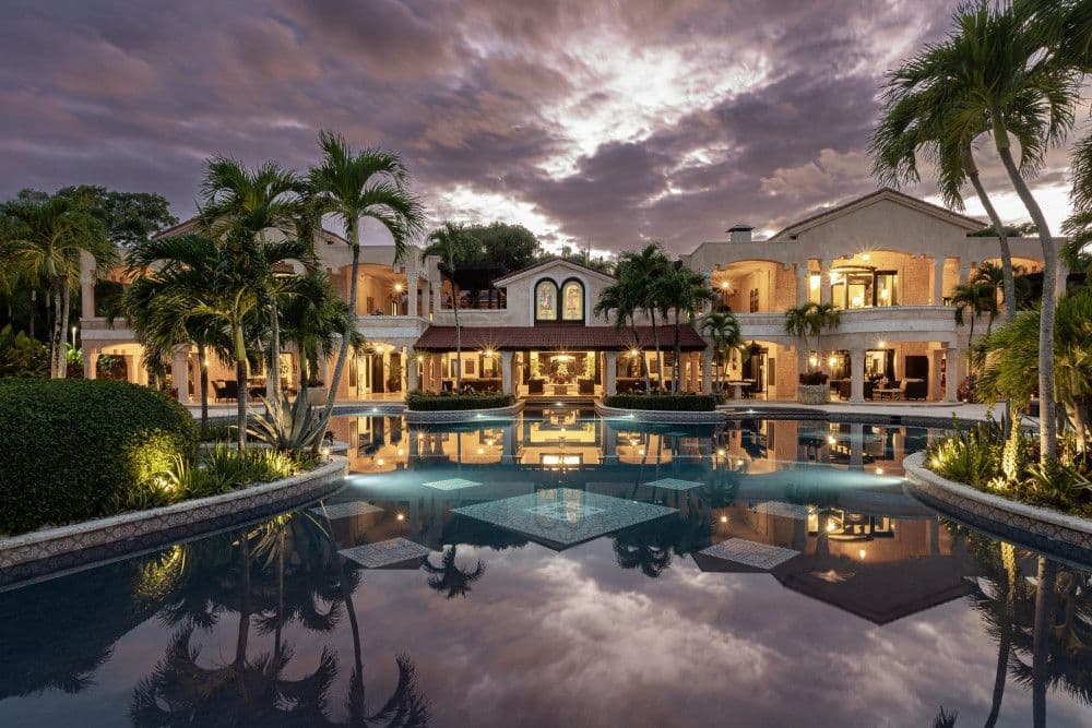 Villa Anacaona lit at dusk with its facade reflected in the pool, Cabrera